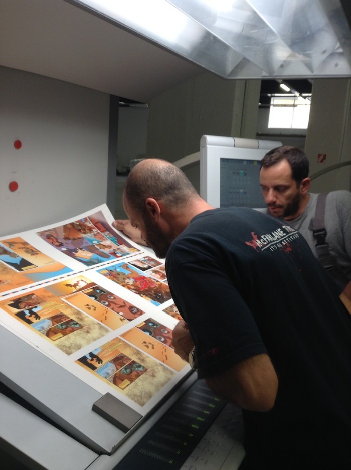 Ο Νίκος Κούτσης, εικονογράφος, εξετάζει τα χρώματα στα πρώτα εκτυπωμένα φύλλα του βιβλίου.